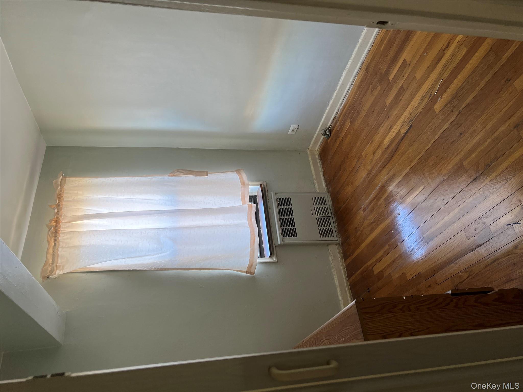 84-20 51st Avenue, Unit 6H Queens, NY 11373 - Photo 2 of 8 a view of an empty room with wooden floor and a window