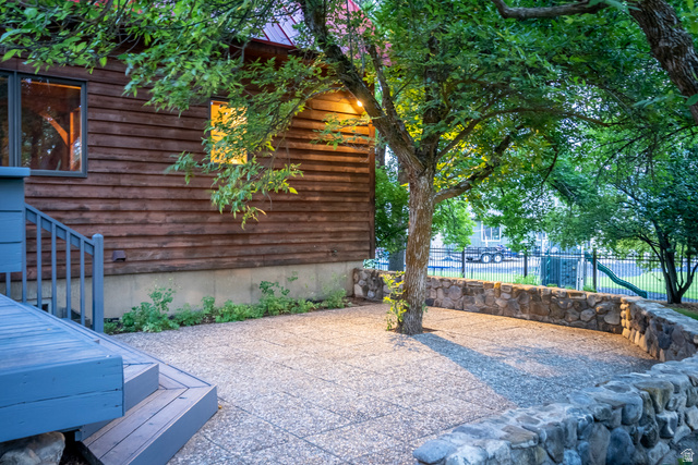 435 Canyon Road Millville, UT 84326 - Photo 57 of 113 Outdoor patio featuring aggregate paving, a curved stone retaining wall, and mature tree landscaping