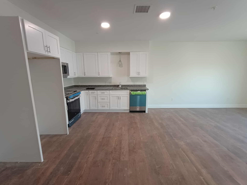 10 Franklin Avenue, Unit 402 Revere, MA 02151 - Photo 3 of 15 a kitchen with stainless steel appliances granite countertop a refrigerator a stove top oven a sink and dishwasher with wooden floor