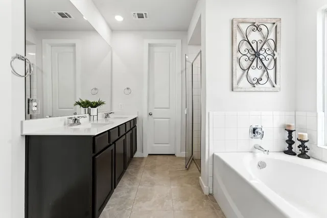 a en suite bathroom with a bathtub double sink and mirror