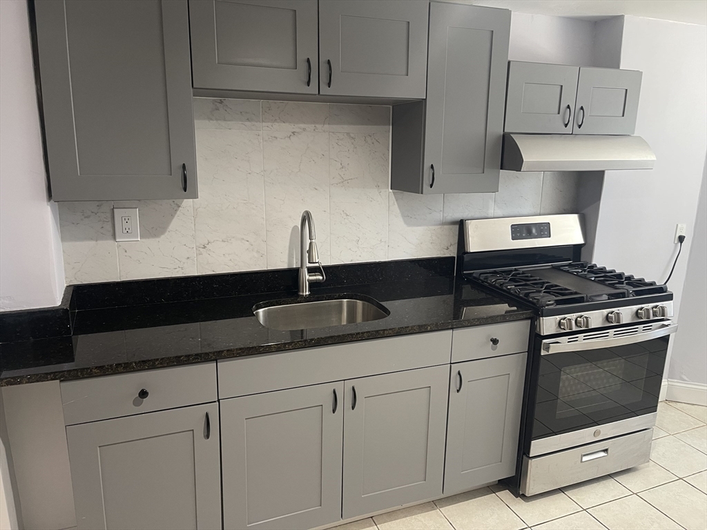 23 Spring Street, Unit B Malden, MA 02148 - Photo 5 of 9 a kitchen with white cabinets and appliances