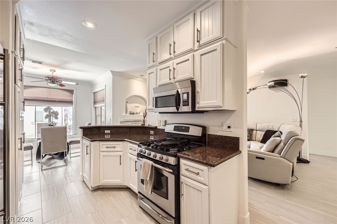 2050 West Warm Springs Road, Unit 3624 Henderson, NV 89014 - Photo 40 of 40 Kitchen featuring appliances with stainless steel finishes, a ceiling fan, open floor plan, dark stone countertops, and a peninsula