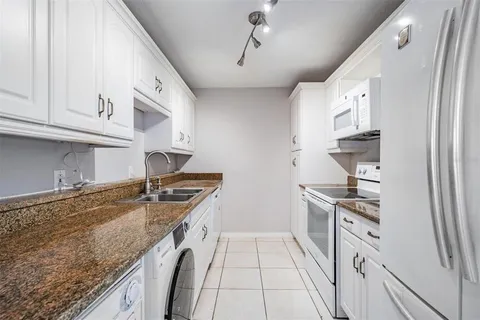 a kitchen with granite countertop a sink stove and cabinets