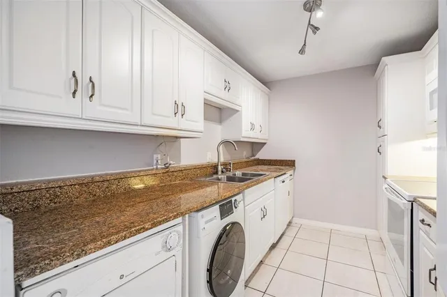 a utility room with granite countertop a sink a washer and dryer
