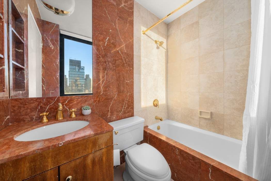 330 East 75th Street, Unit 28BC Manhattan, NY 10021 - Photo 16 of 20 a bathroom with a granite countertop sink toilet and shower