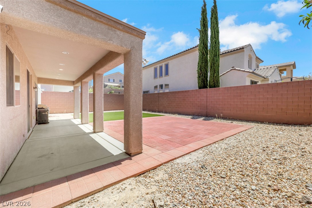 2501 Bechamel Place Henderson, NV 89044 - Photo 44 of 50 A private backyard oasis awaits, featuring a covered patio and a neat brick paver area perfect for outdoor relaxation.