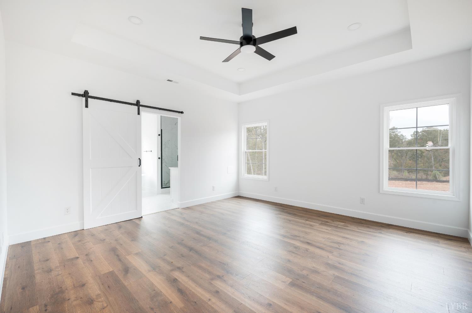 11218 Leesville Road Evington, VA 24550 - Photo 17 of 54 an empty room with wooden floor ceiling fan and windows