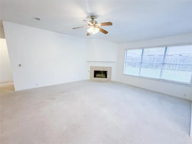 an empty room with chandelier fan and windows