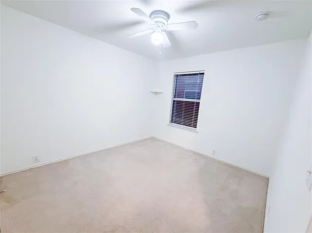 an empty room with a window and ceiling fan