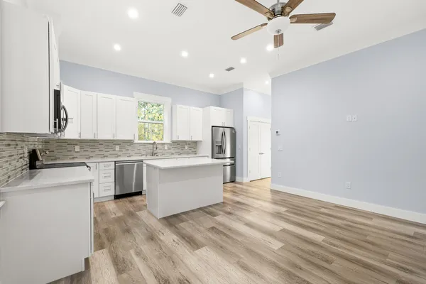 a large kitchen with a lot of counter space and wooden floor
