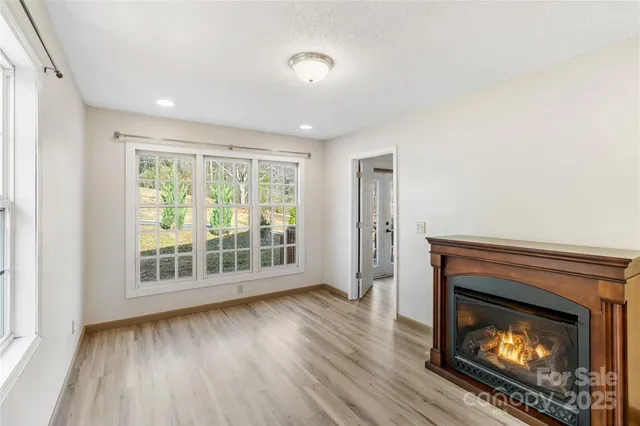 a view of an empty room with wooden floor fireplace and a window
