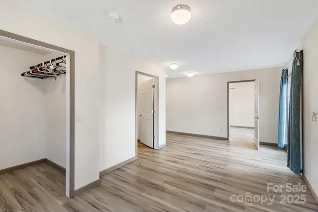 a view of an empty room with wooden floor and a ceiling fan