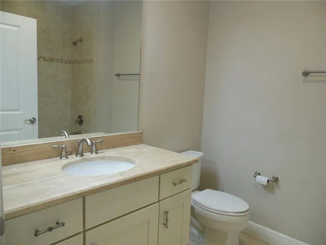 a bathroom with a granite countertop sink a toilet and a mirror
