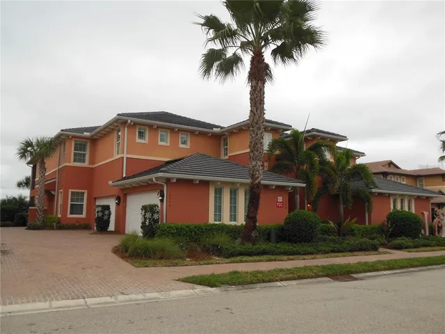 a front view of a house with a garden and palm trees