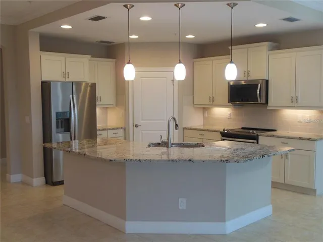 a kitchen with stainless steel appliances granite countertop a sink a stove and a refrigerator