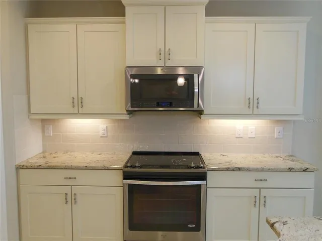 a kitchen with granite countertop white cabinets and a stove