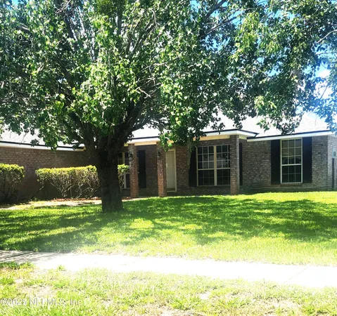 a white house with a big yard and large trees