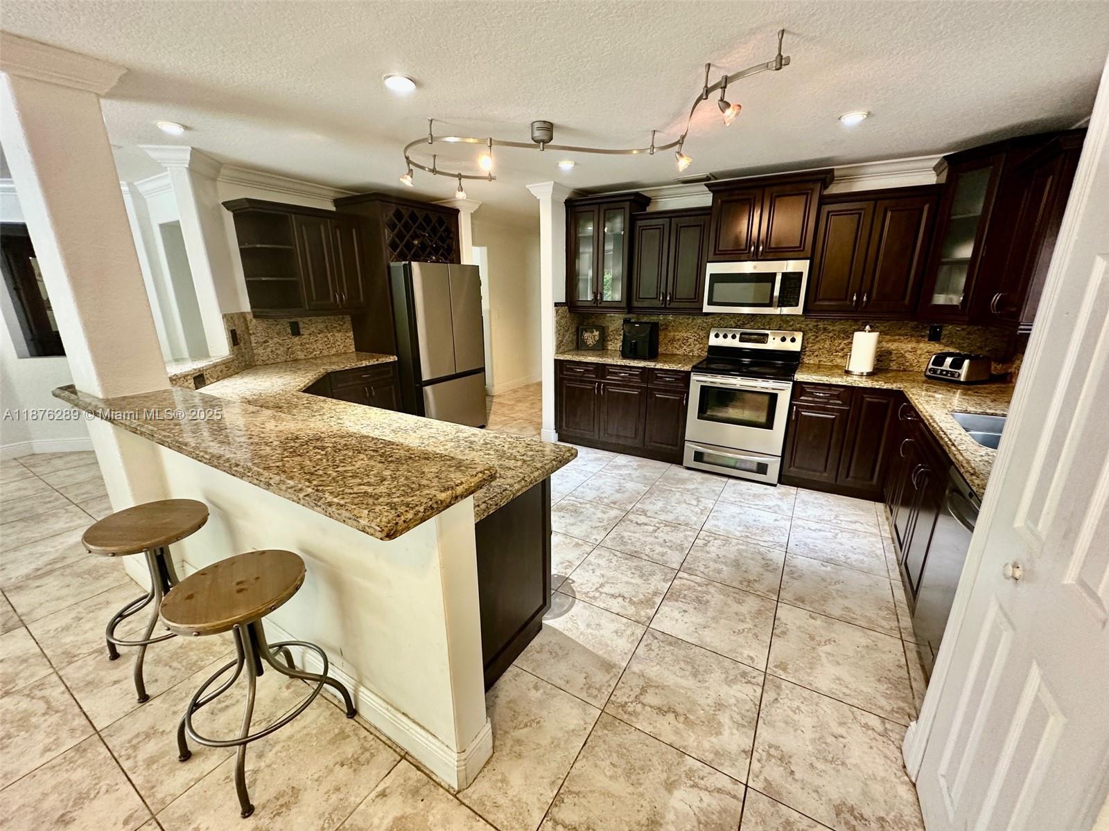 16335 Southwest 93rd Street Miami, FL 33196 - Photo 11 of 29 a kitchen with stainless steel appliances granite countertop a sink and a stove