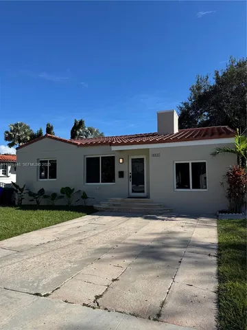 a front view of house with yard and trees in the background