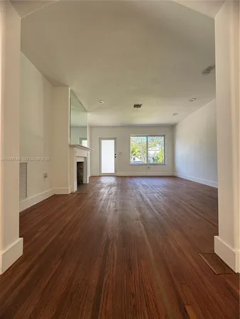 an empty room with wooden floor and window