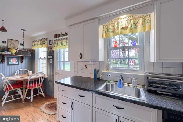 a kitchen with stainless steel appliances granite countertop sink a table and chairs in it