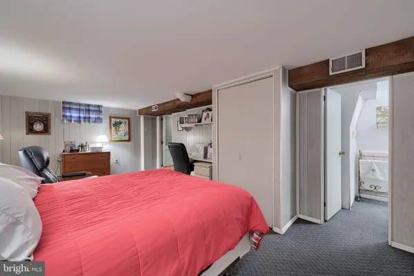 a bed sitting in a bedroom next to a window with kitchen view