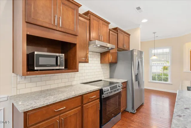 a kitchen with stainless steel appliances granite countertop a refrigerator a stove and a wooden cabinets
