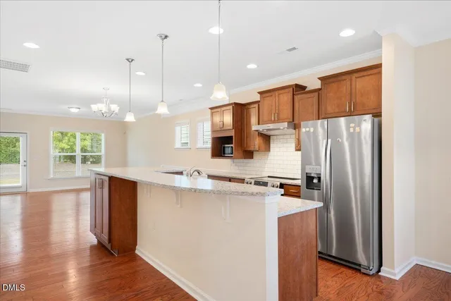 a kitchen with stainless steel appliances a refrigerator a sink dishwasher a stove and white cabinets with wooden floor