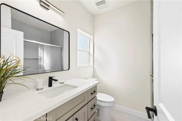 a bathroom with a granite countertop sink toilet and mirror