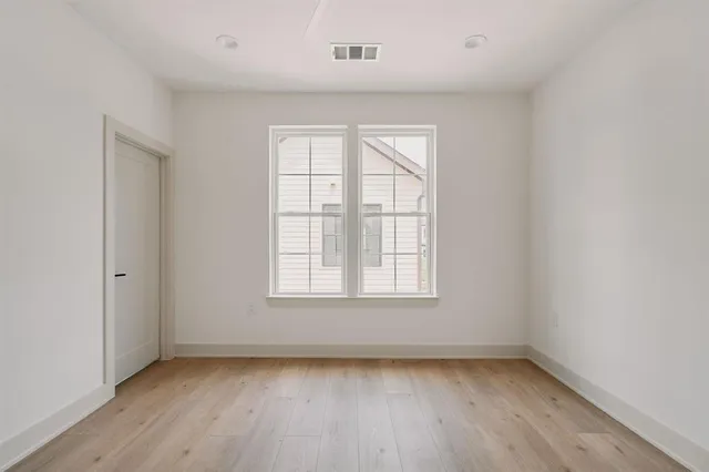 an empty room with wooden floor and windows