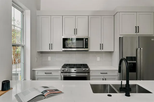 a kitchen with granite countertop a stove a sink and a refrigerator