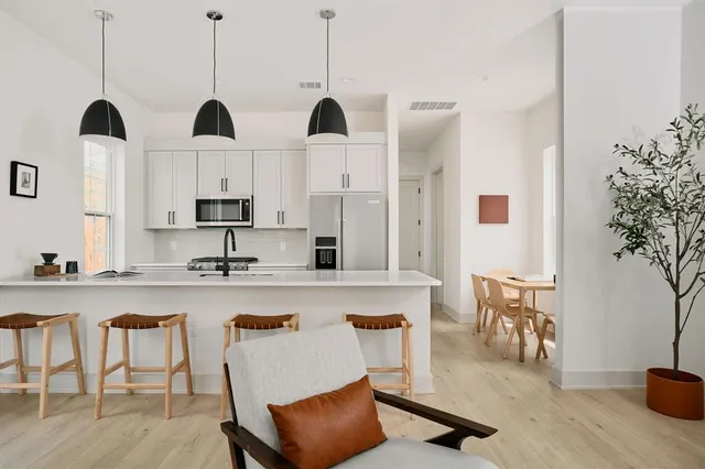 a kitchen with stainless steel appliances granite countertop a table chairs in it and white cabinets