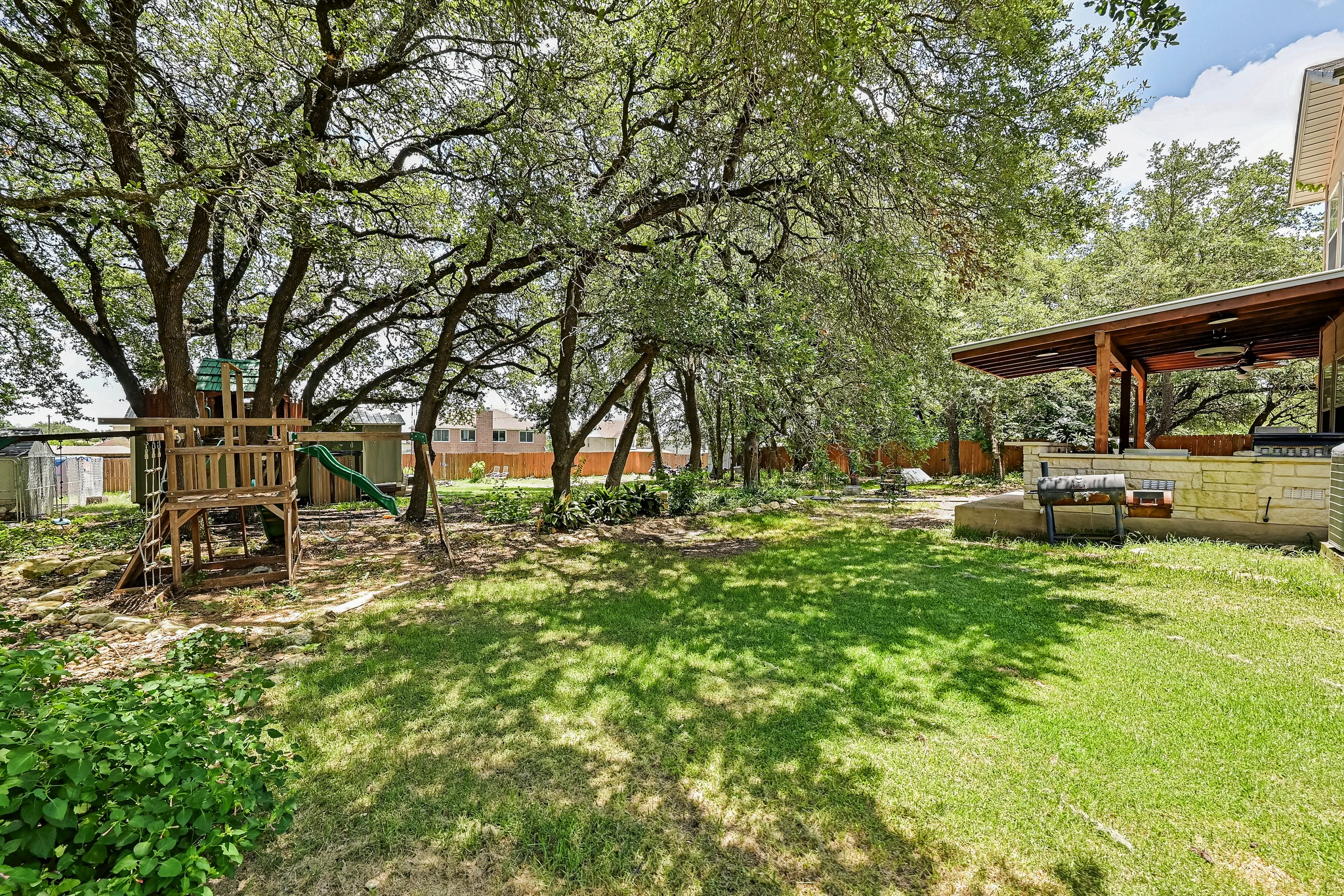 104 North Sumac Lane Georgetown, TX 78633 - Photo 40 of 40 A spacious backyard retreat features mature trees, a play structure, and an outdoor entertaining area.