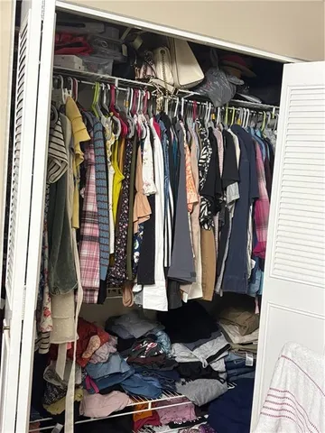 a view of walk in closet with clothes and shoes