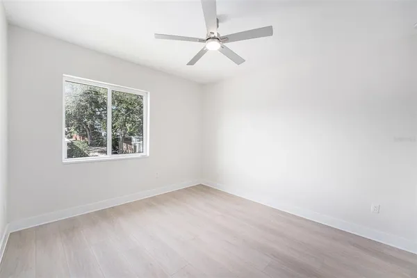 an empty room with a window and a fan