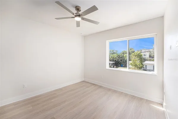 an empty room with a window and a fan