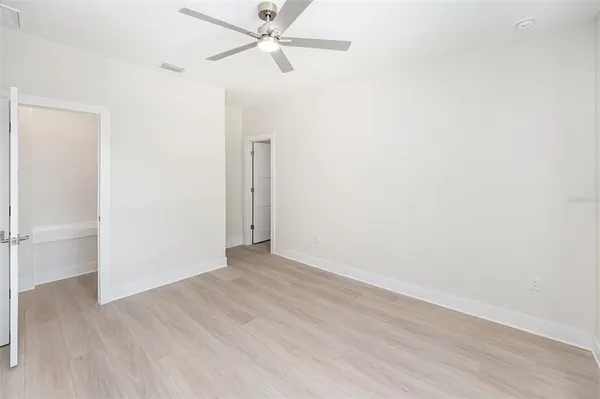 an empty room with wooden floor closet and fan