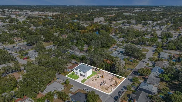 an aerial view of a residential houses with outdoor space and trees