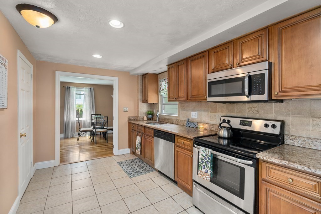27 Upland Road Brockton, MA 02301 - Photo 6 of 25 a kitchen with stainless steel appliances granite countertop a stove top oven a sink dishwasher a dining table and chairs with wooden floor