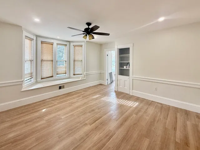 a view of an empty room with a window and wooden floor