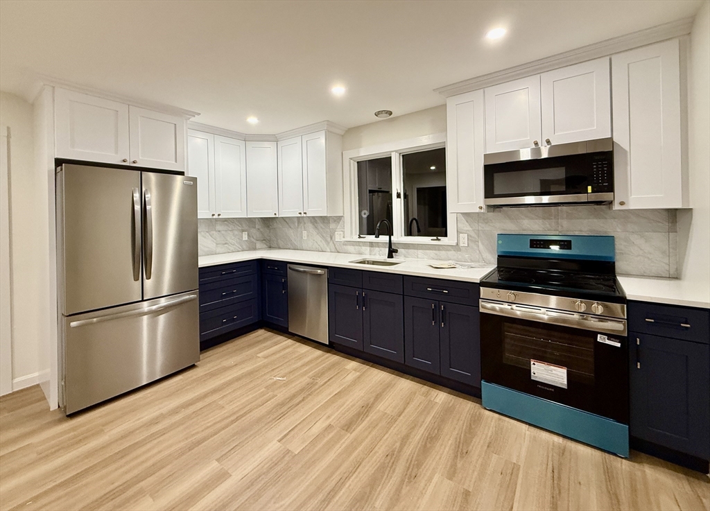 225 Pleasant Street, Unit 1 Weymouth, MA 02190 - Photo 4 of 10 a kitchen with stainless steel appliances granite countertop a refrigerator stove a sink dishwasher and microwave with wooden floor