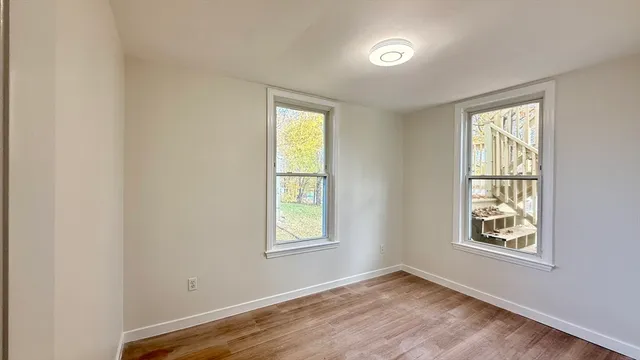a view of an empty room with a window and wooden floor