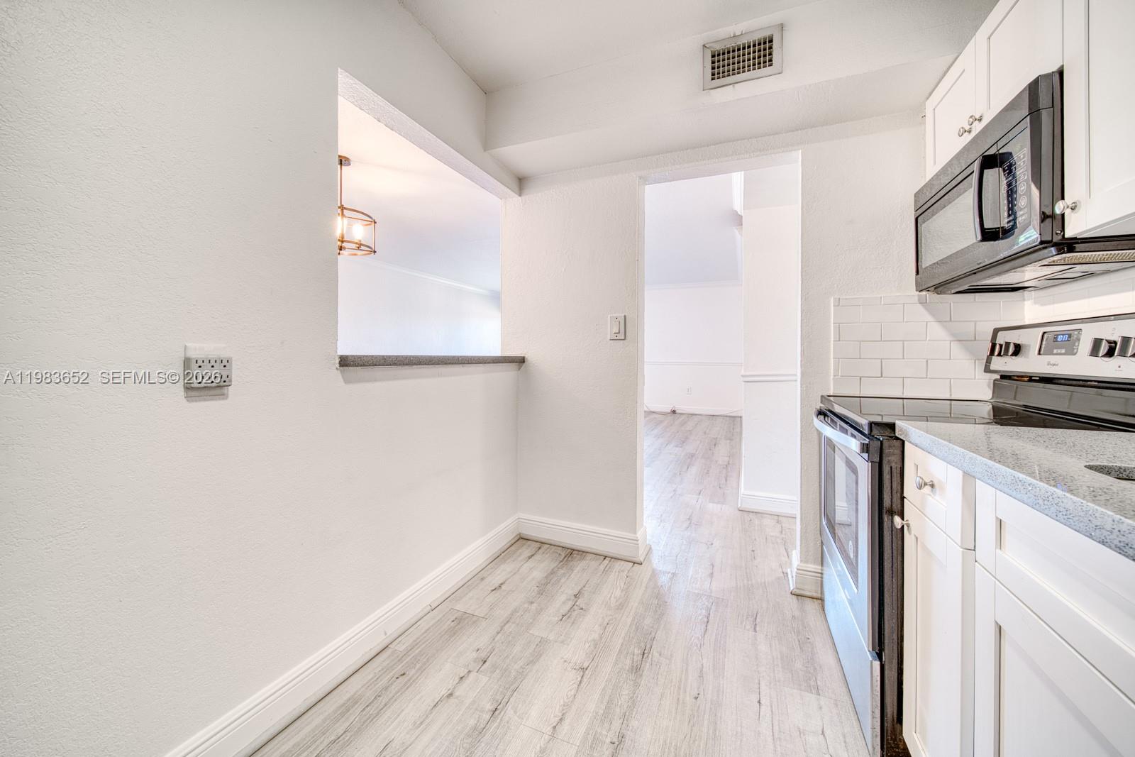 9459 Southwest 76th Street, Unit R5 Miami, FL 33173 - Photo 9 of 33 a kitchen with a wooden floor