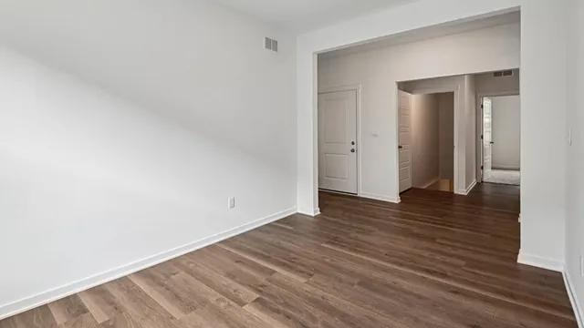a view of an empty room with wooden floor and closet