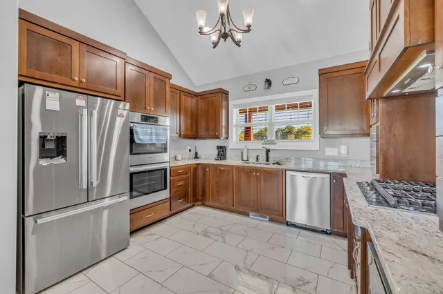 a kitchen with granite countertop stainless steel appliances a stove sink and refrigerator