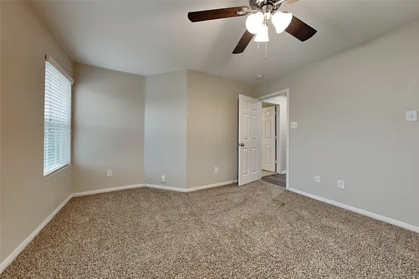 a view of an empty room with window and chandelier fan