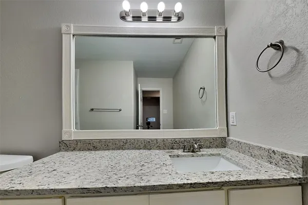 a bathroom with a granite countertop sink and a mirror