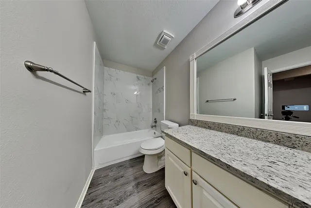 a bathroom with a granite countertop sink a toilet and shower