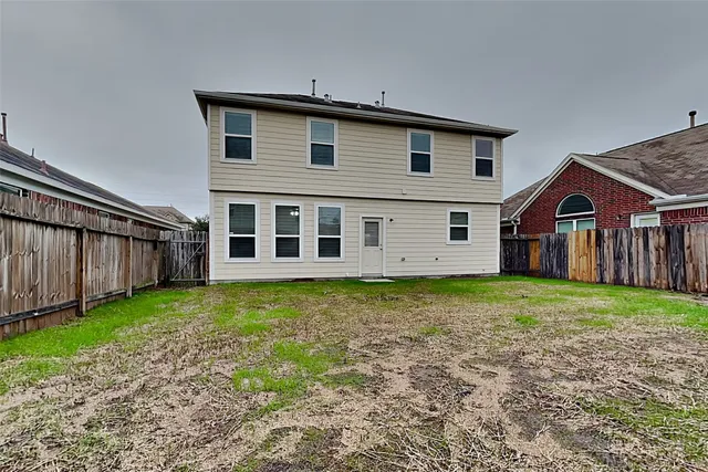 a view of a yard in front of a house with wooden fence