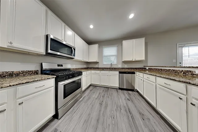 a white kitchen with granite countertop stainless steel appliances